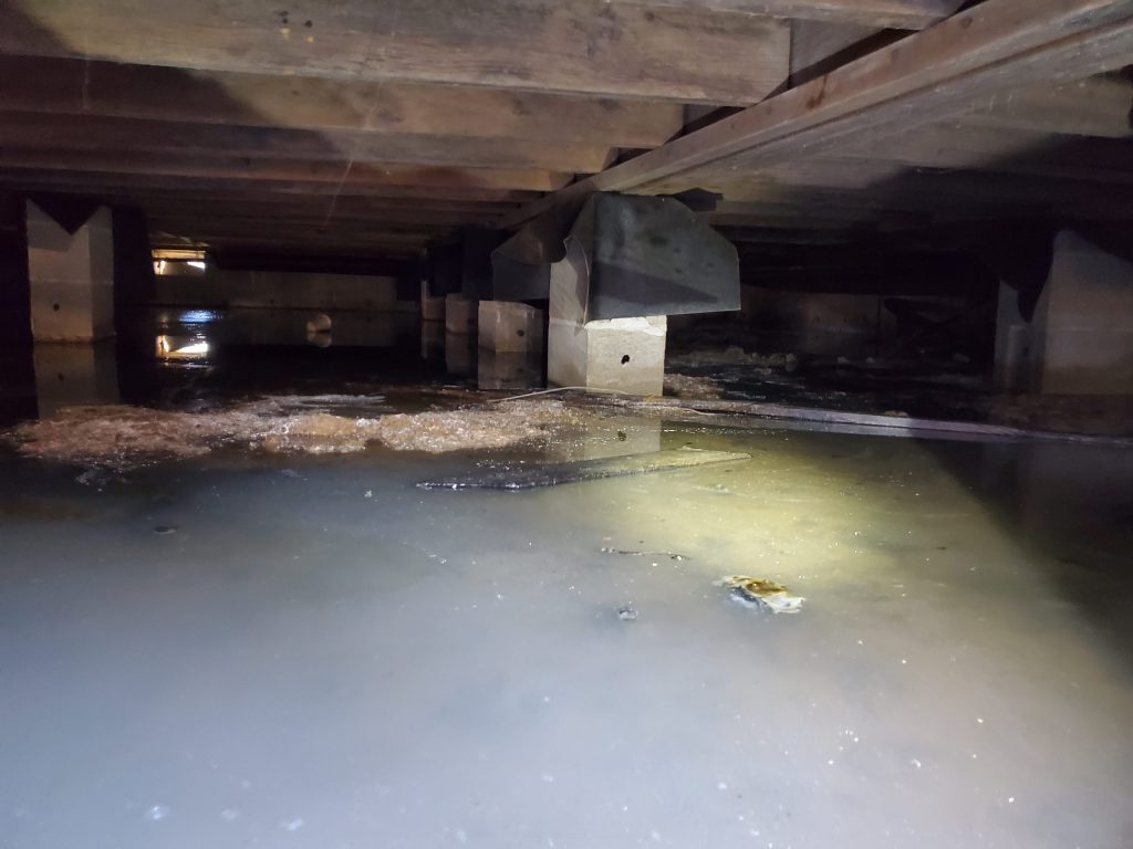 Standing water in a flooded crawl space after a Portland storm